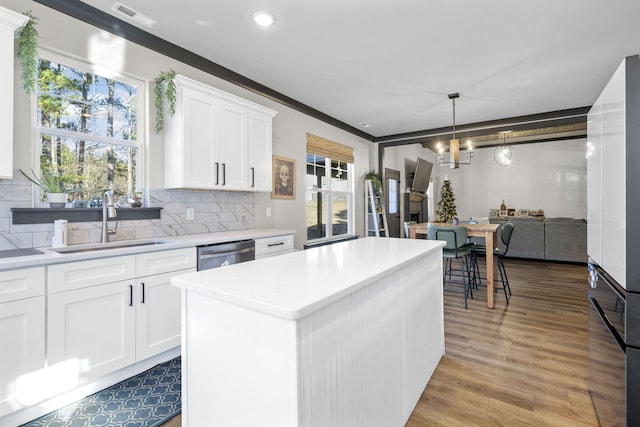 kitchen with a center island, dishwasher, sink, tasteful backsplash, and white cabinets