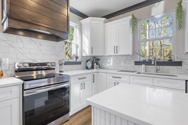 kitchen featuring white cabinetry, electric range, sink, and custom range hood