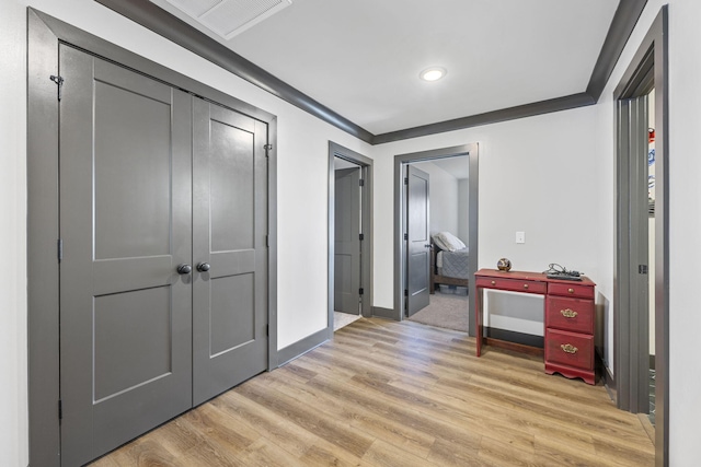 hall with light wood-type flooring and ornamental molding