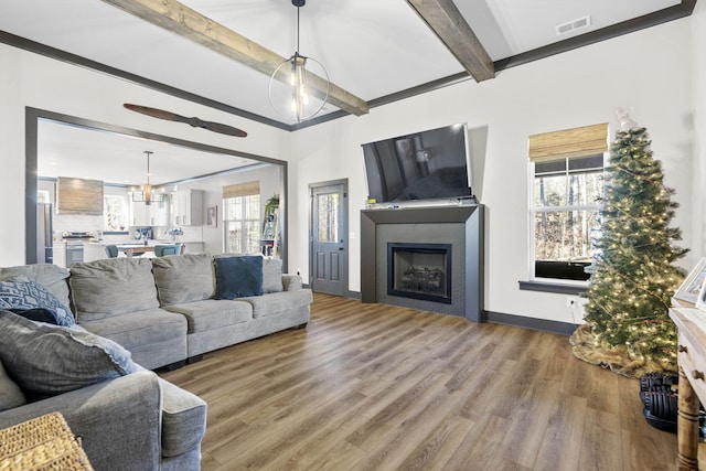 living room featuring beam ceiling, a wealth of natural light, a notable chandelier, and hardwood / wood-style flooring