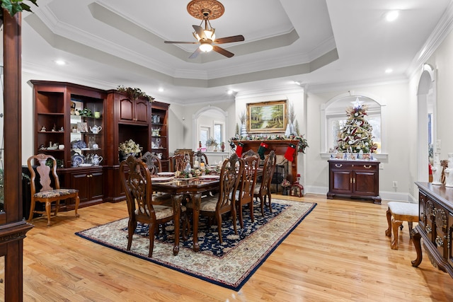 dining area featuring a tray ceiling, ceiling fan, a healthy amount of sunlight, crown molding, and light hardwood / wood-style flooring