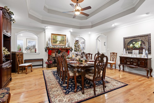 dining area with ceiling fan, light hardwood / wood-style floors, crown molding, and a tray ceiling