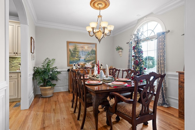 dining room featuring ornamental molding, light wood-type flooring, and a notable chandelier