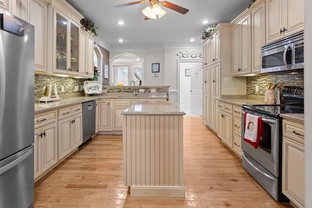 kitchen featuring a center island, backsplash, stainless steel appliances, and cream cabinets