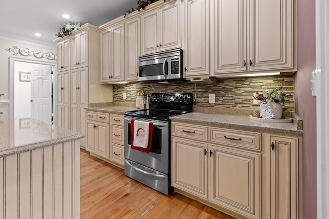 kitchen featuring cream cabinets, crown molding, light stone countertops, appliances with stainless steel finishes, and tasteful backsplash