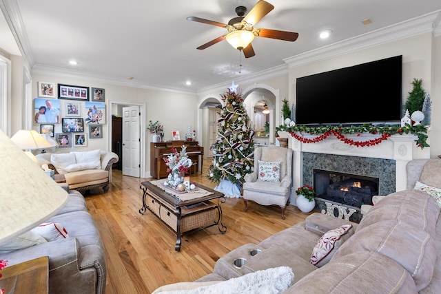 living room with hardwood / wood-style floors, ceiling fan, ornamental molding, and a fireplace