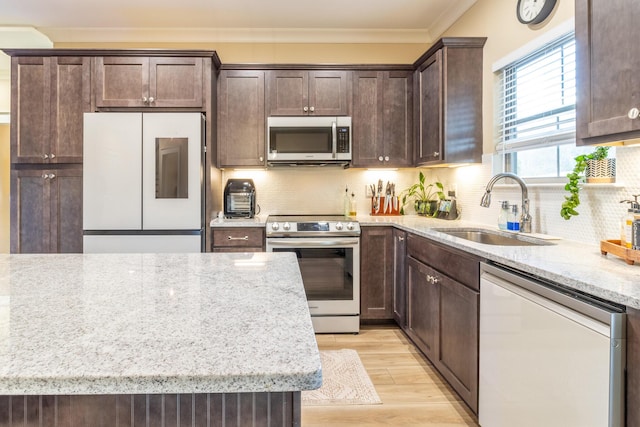 kitchen featuring light stone countertops, stainless steel appliances, tasteful backsplash, sink, and crown molding