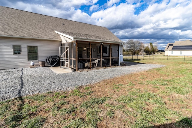 rear view of property with a sunroom, a lawn, and a patio