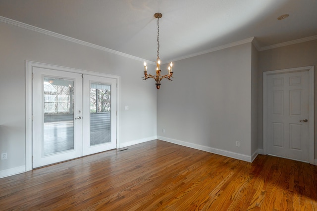 empty room featuring a chandelier, french doors, ornamental molding, and hardwood / wood-style floors