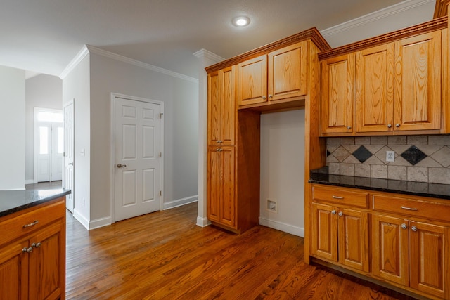 kitchen with dark hardwood / wood-style floors, crown molding, dark stone counters, and tasteful backsplash