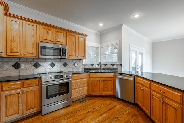 kitchen featuring sink, decorative backsplash, ornamental molding, kitchen peninsula, and stainless steel appliances