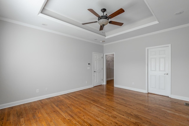 spare room featuring a tray ceiling, ceiling fan, hardwood / wood-style floors, and ornamental molding