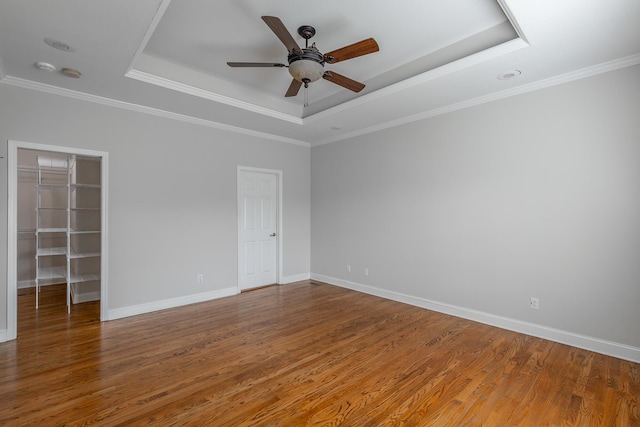 spare room with ceiling fan, a raised ceiling, ornamental molding, and wood-type flooring