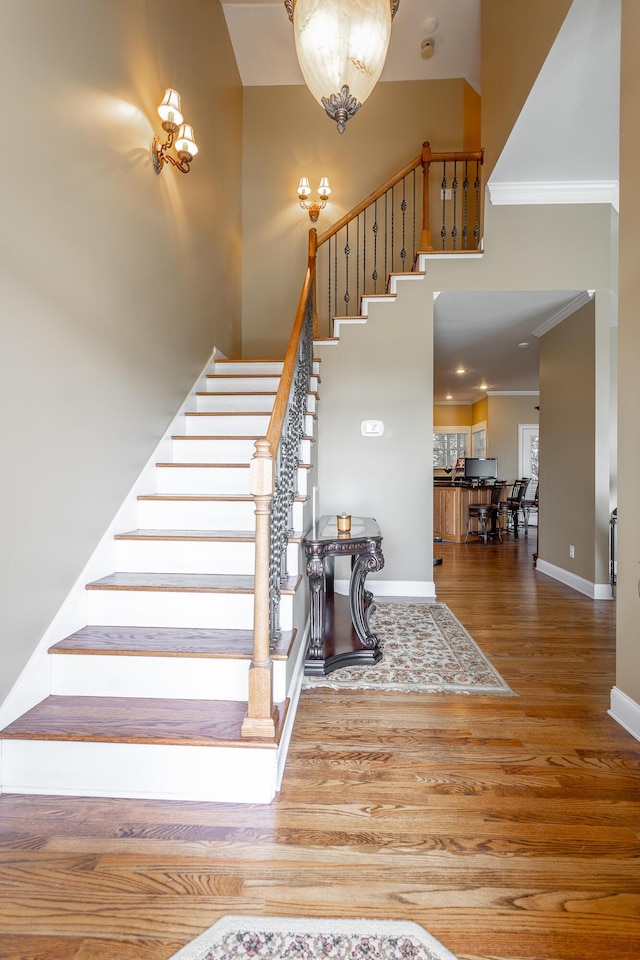 staircase with hardwood / wood-style floors and crown molding