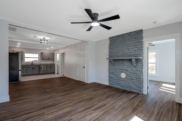 unfurnished living room featuring ceiling fan, sink, and dark wood-type flooring