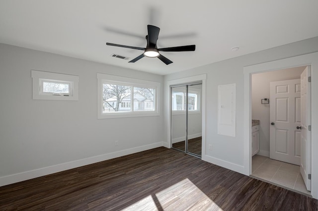 unfurnished bedroom featuring dark hardwood / wood-style flooring, ceiling fan, and a closet