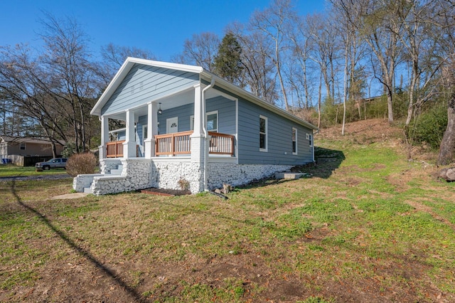 view of side of property featuring covered porch and a yard