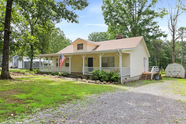 view of front of property with covered porch, a shed, and a front yard