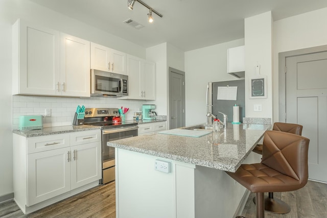 kitchen featuring backsplash, light stone countertops, white cabinetry, and stainless steel appliances