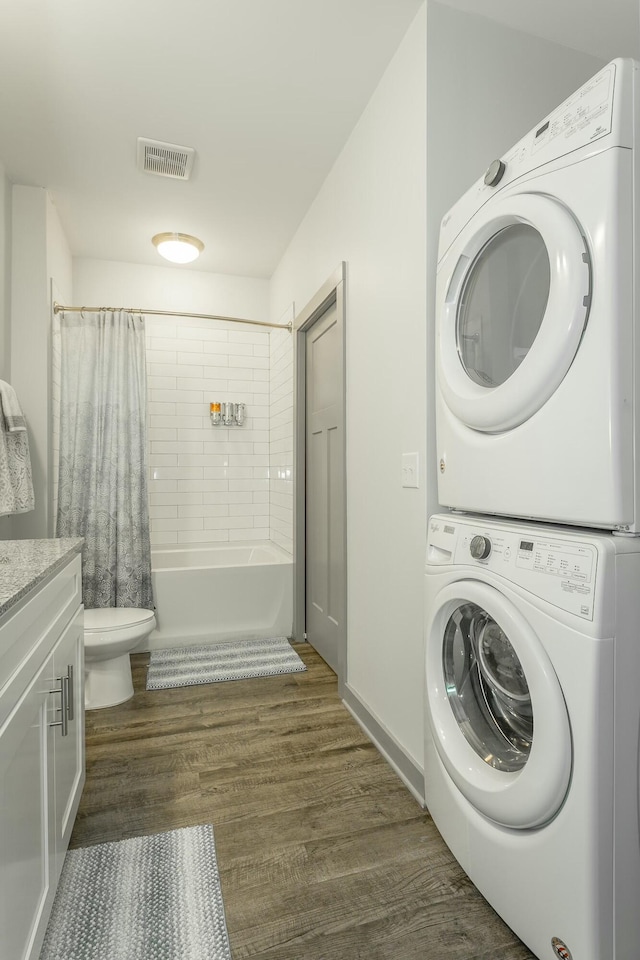 washroom featuring dark hardwood / wood-style flooring and stacked washing maching and dryer