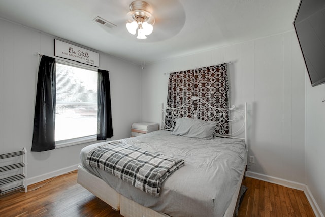 bedroom featuring hardwood / wood-style floors, ceiling fan, and multiple windows