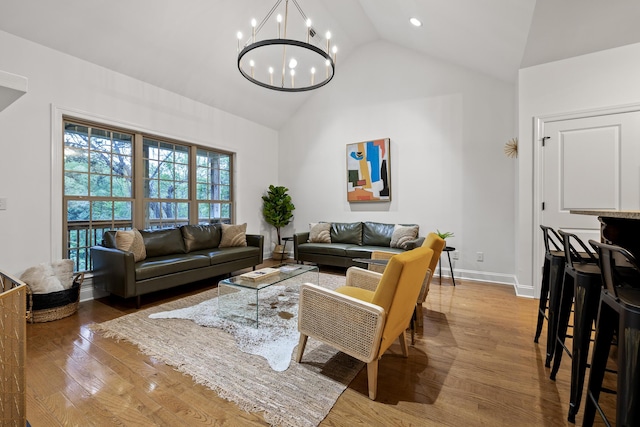 living room featuring hardwood / wood-style floors, lofted ceiling, and a chandelier