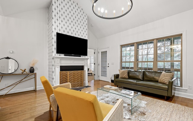 living room with a chandelier, a large fireplace, hardwood / wood-style flooring, and high vaulted ceiling