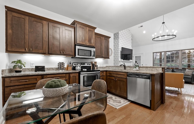 kitchen with light stone countertops, appliances with stainless steel finishes, pendant lighting, and a notable chandelier