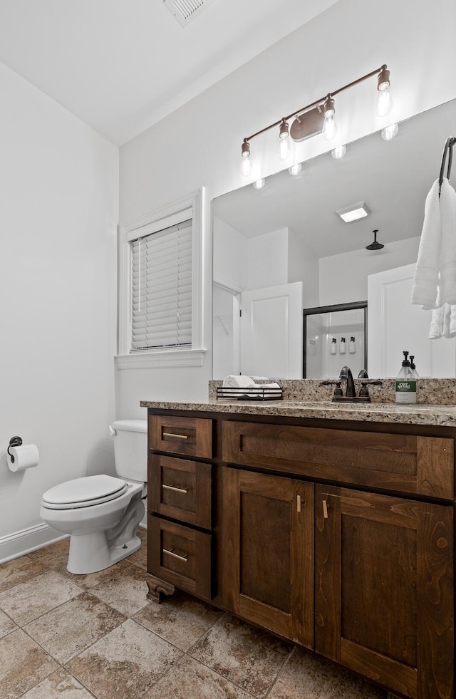 bathroom featuring vanity, toilet, and a shower with door