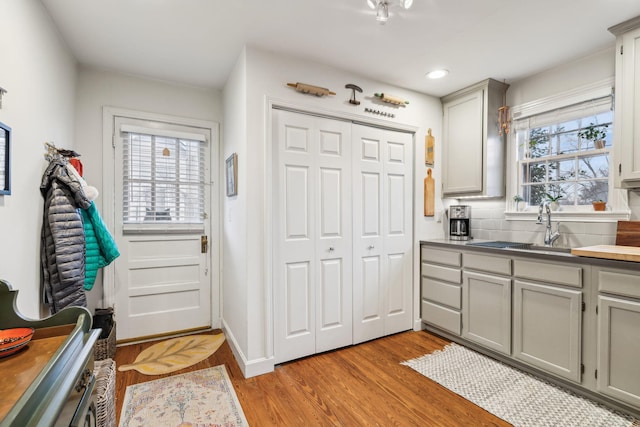 interior space featuring decorative backsplash, gray cabinets, light hardwood / wood-style floors, and sink