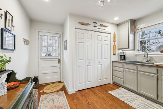 kitchen with backsplash, gray cabinetry, a wealth of natural light, and light wood-type flooring