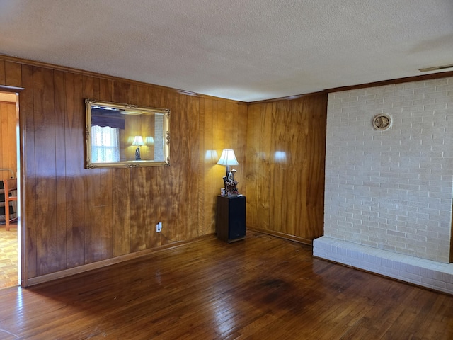 unfurnished room with wooden walls, wood-type flooring, and ornamental molding