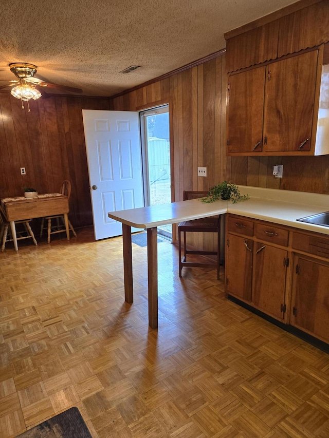 kitchen featuring ceiling fan, wooden walls, and light parquet floors