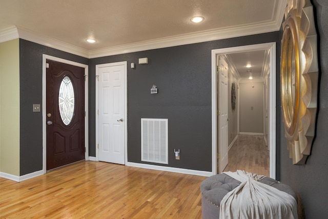 entrance foyer with ornamental molding and light hardwood / wood-style flooring