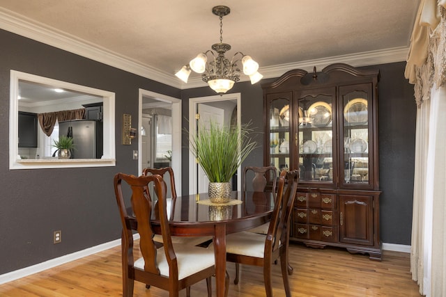 dining space featuring light hardwood / wood-style flooring, a chandelier, and ornamental molding