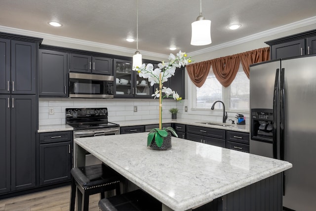 kitchen featuring sink, decorative backsplash, appliances with stainless steel finishes, decorative light fixtures, and a kitchen island