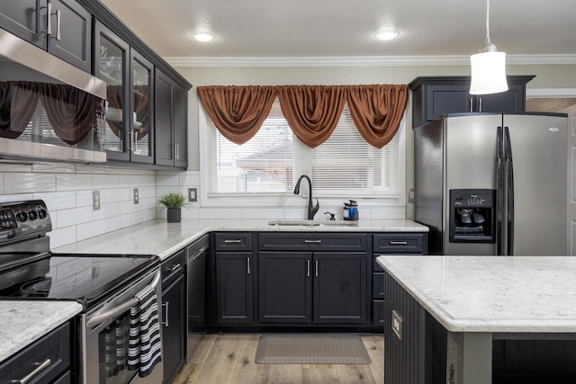 kitchen with sink, hanging light fixtures, stainless steel appliances, light hardwood / wood-style flooring, and crown molding