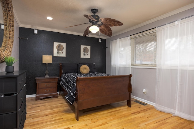 bedroom with ceiling fan, crown molding, and light hardwood / wood-style flooring