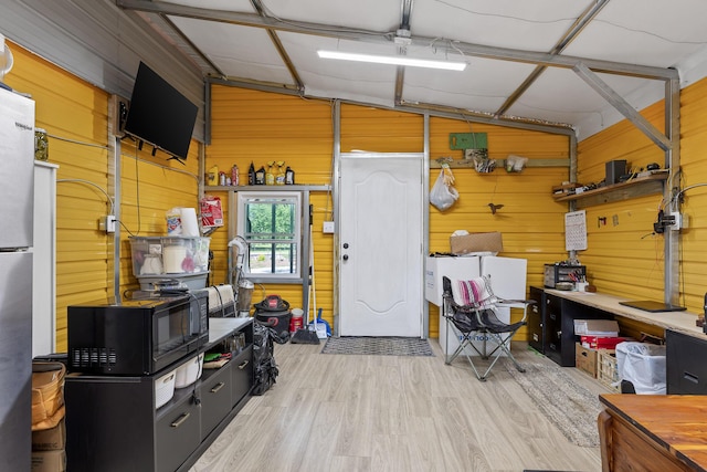 interior space featuring wooden walls and stainless steel refrigerator