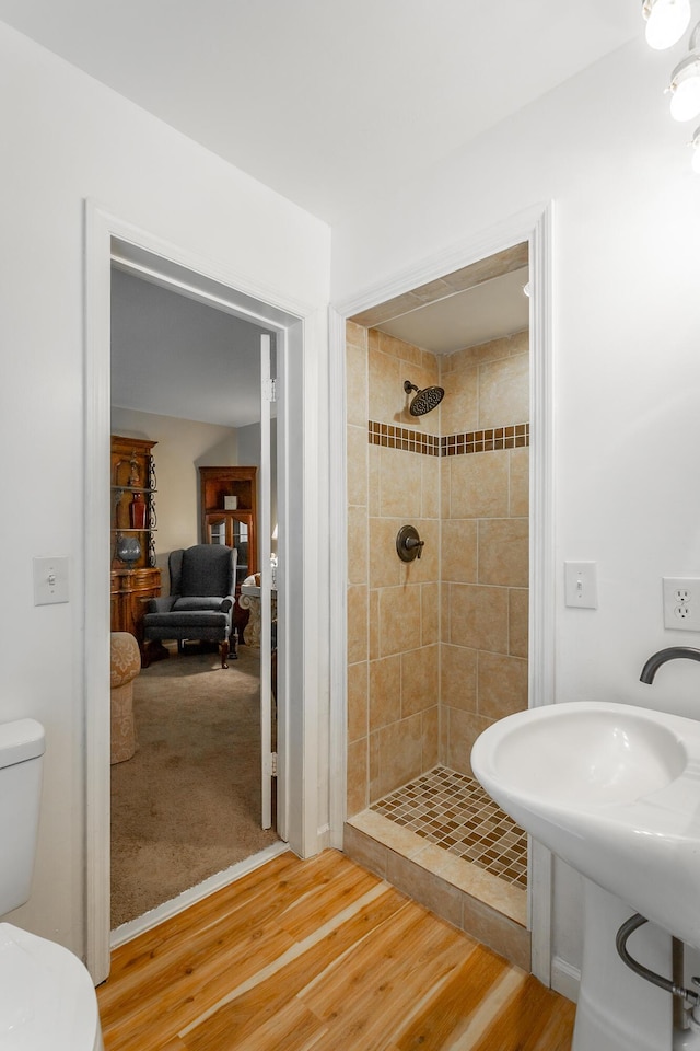 bathroom featuring tiled shower, hardwood / wood-style flooring, and toilet