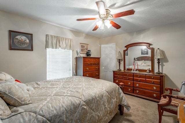 carpeted bedroom featuring ceiling fan and a textured ceiling