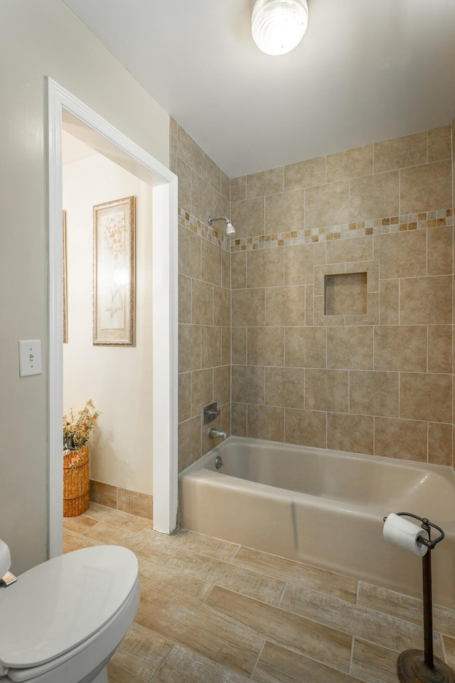 bathroom with tiled shower / bath combo and toilet