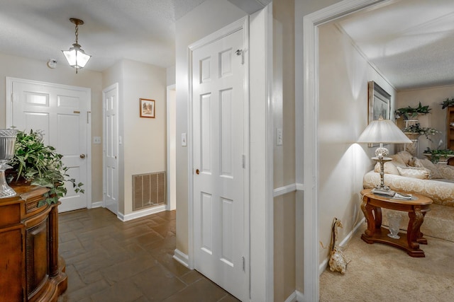 hallway featuring dark colored carpet and a textured ceiling