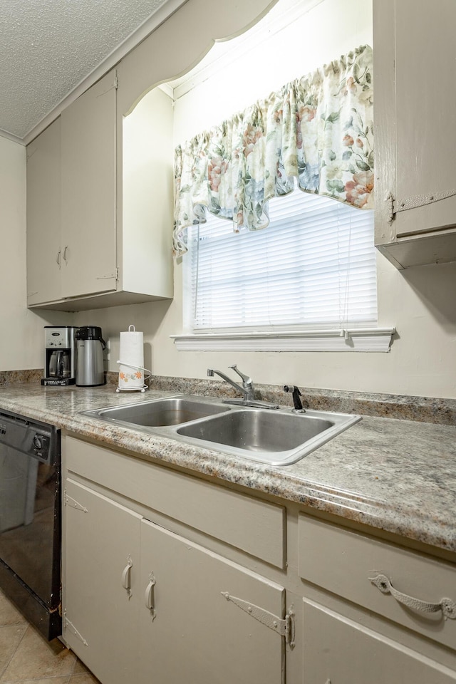 kitchen featuring a textured ceiling, light tile patterned flooring, sink, and black dishwasher