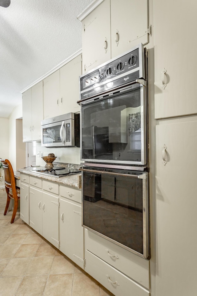 kitchen with light tile patterned floors, a textured ceiling, double oven, and gas cooktop