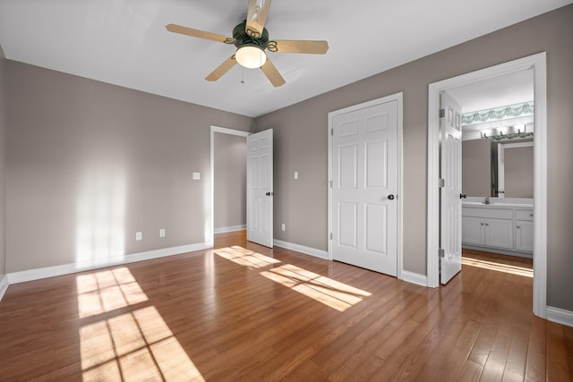 unfurnished bedroom with ceiling fan, wood-type flooring, a closet, and ensuite bath