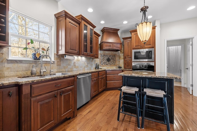 kitchen featuring premium range hood, dishwasher, built in microwave, a kitchen island, and sink