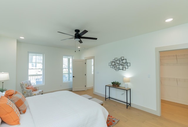 bedroom with ceiling fan, light hardwood / wood-style floors, a walk in closet, and a closet