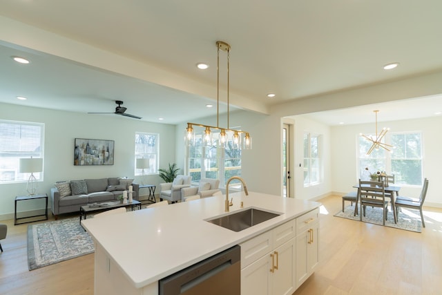 kitchen featuring pendant lighting, dishwasher, a center island with sink, white cabinets, and sink