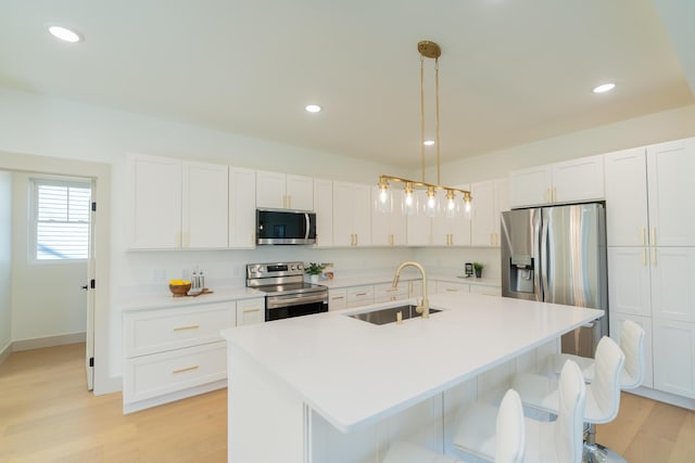 kitchen featuring sink, an island with sink, hanging light fixtures, and appliances with stainless steel finishes